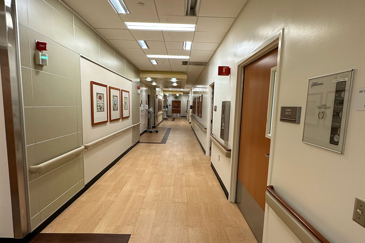 Renovated hospital corridor with new wood-look flooring, handrails, and wall protection