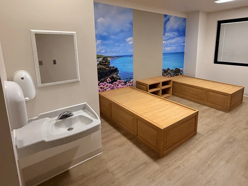 Anti-ligature behavioral health patient room with platform beds, flush-mount sink, and therapeutic mural at Canyon Ridge