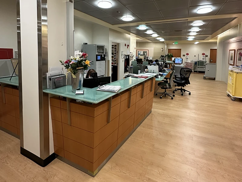 Completed medical office nurse station with green glass counter and wood flooring renovated by Selvaggi Built